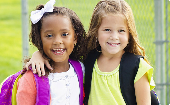 two young school girls smiling with arms around each other